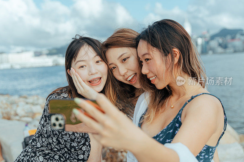 三个年轻的亚洲女性朋友在海边用智能手机自拍
