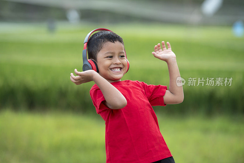 蹒跚学步的男孩用耳机听音乐