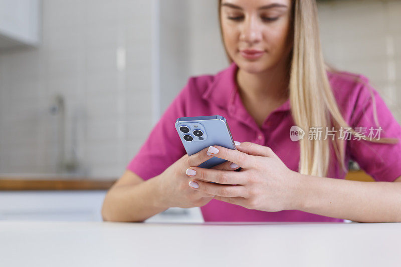 年轻的金发女子在现代蓝色智能手机上的信使应用程序中输入消息。金发女孩用手机发短信