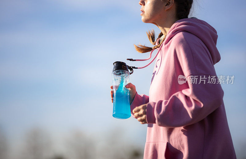 年轻女子在公园慢跑时补水。