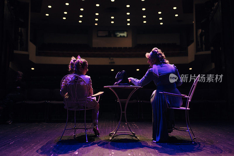 两个职业女演员晚上在剧院舞台上排练剧本