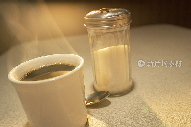日出时分，餐厅里只有一杯热气腾腾的咖啡和一个糖机