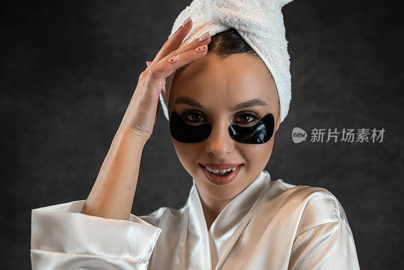 美丽的年轻女子做抗衰老程序与眼罩为完美的皮肤隔离在黑暗