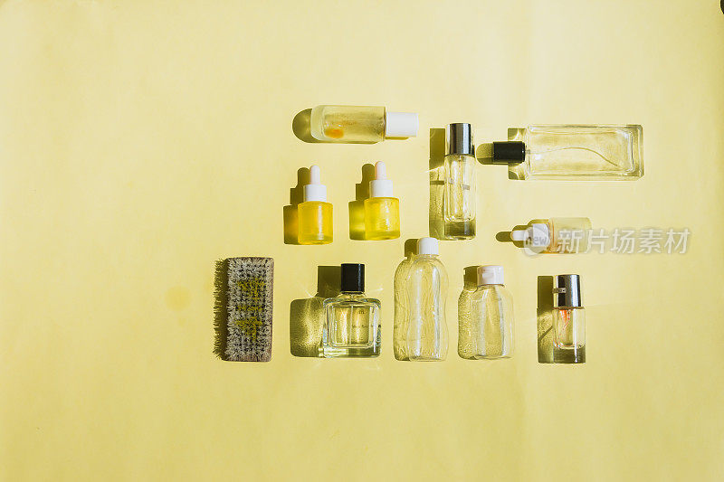 化妆品、香水、身体护理用品的空瓶子，黄色背景的刷子。美容和化妆品的回收、再利用和可持续性