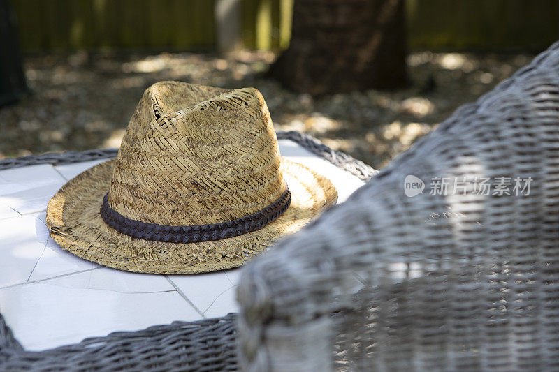 草帽放在花园的桌子上，在斑驳的阳光下