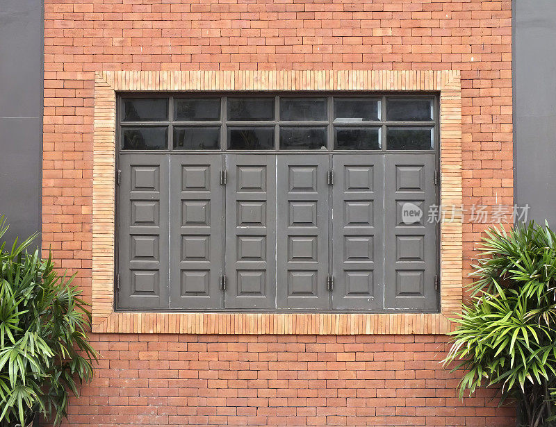 一个有窗户和消防栓的砖砌建筑的照片，有一个有窗户和消防栓的红砖砌建筑。
