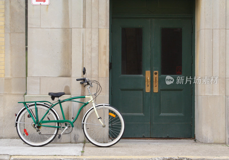 靠在水泥墙和绿色门上的老式自行车