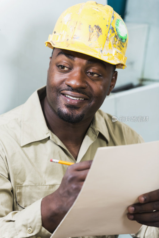 非裔美国工人戴着安全帽，在写字