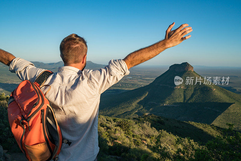 年轻人在山顶上张开双臂