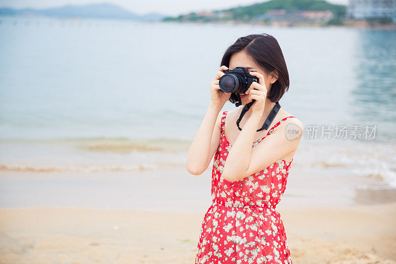 快乐的女人度假摄影与相机在海滩上