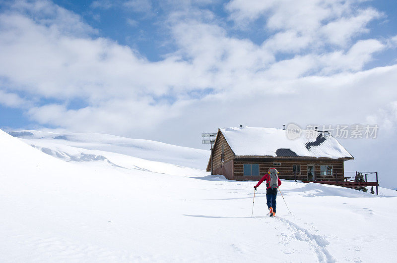 男子滑雪旅游山与边远地区小屋的背景