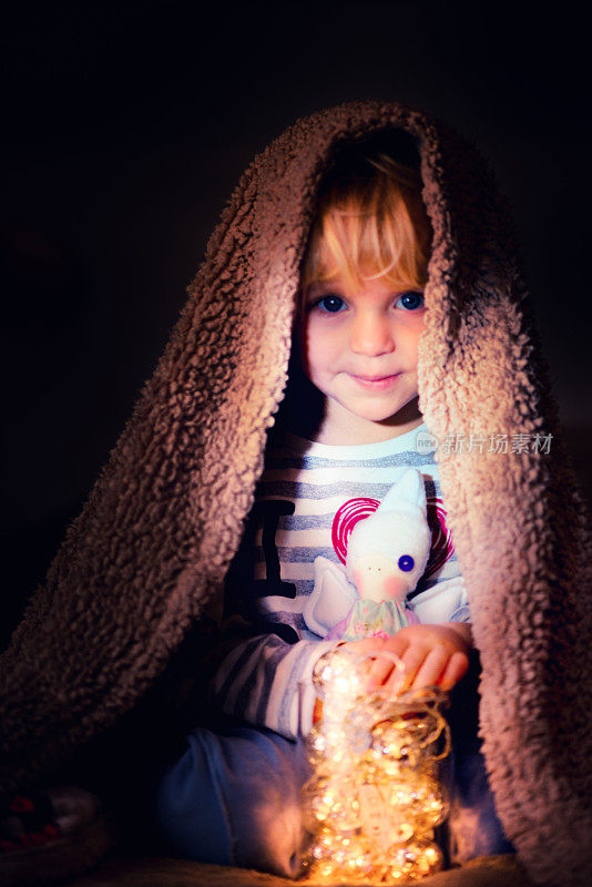 毯子下的女婴抱着一个玩具天使