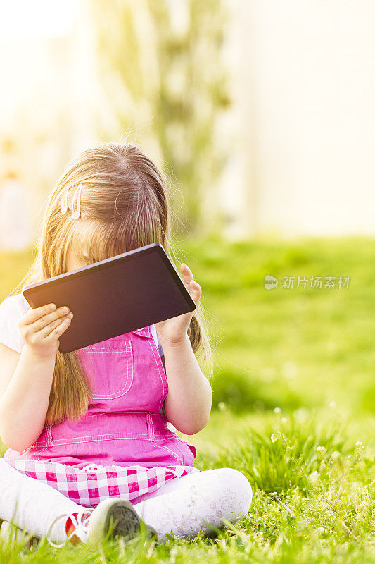 小女孩在大自然中看着数字平板电脑