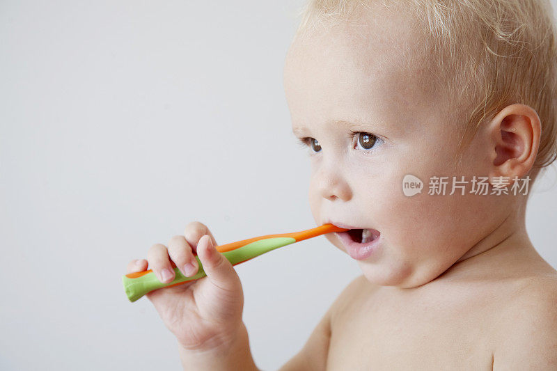 牙齿清洁。小卷发男孩正在用牙刷刷牙。