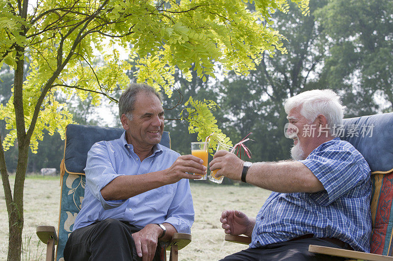 两个老年人在花园里喝橙汁