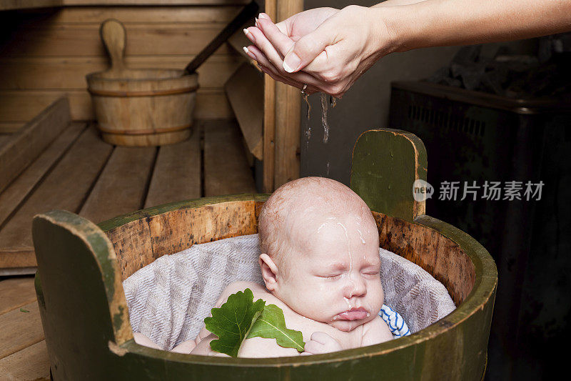 在乡村桑拿浴中，妈妈给宝宝浇水