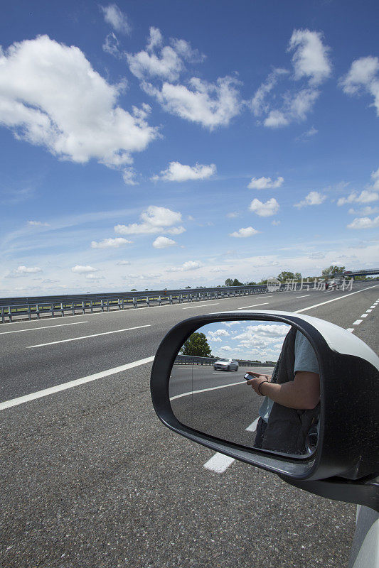 男人使用智能手机的汽车后视镜