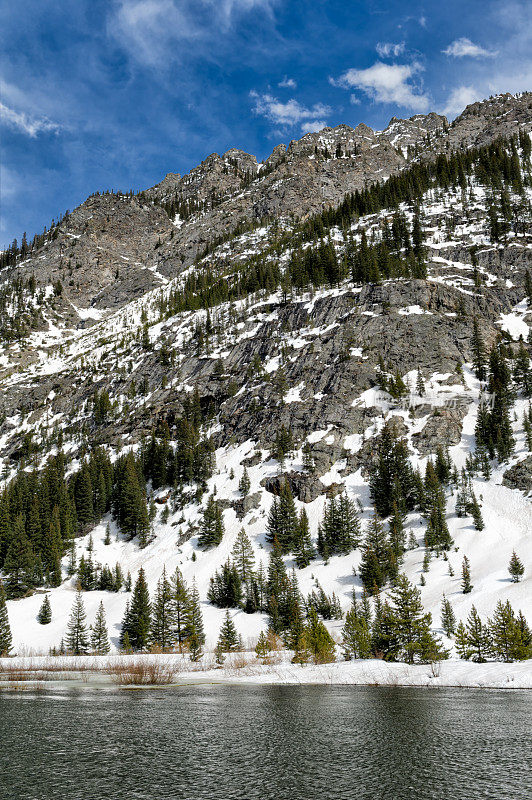 岩石山景观与雪和湖，春天的颜色