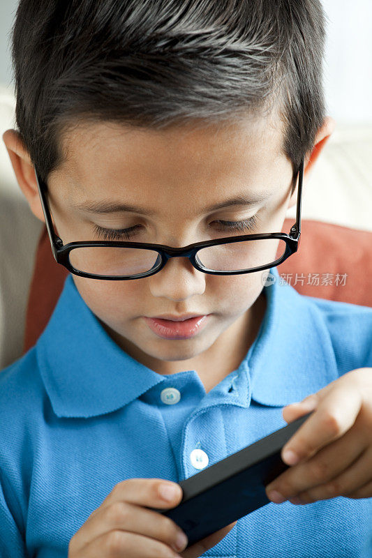 戴眼镜的孩子在玩智能手机