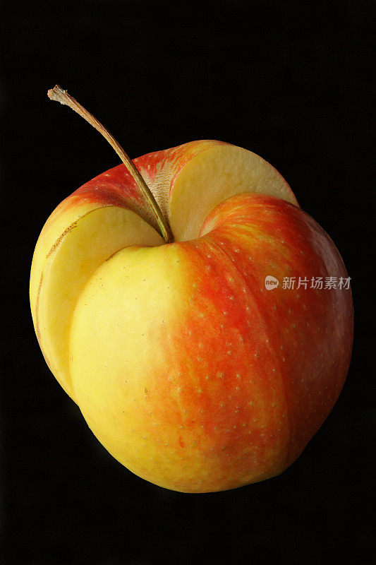 切片黄红苹果在黑色的背景上一分为二
