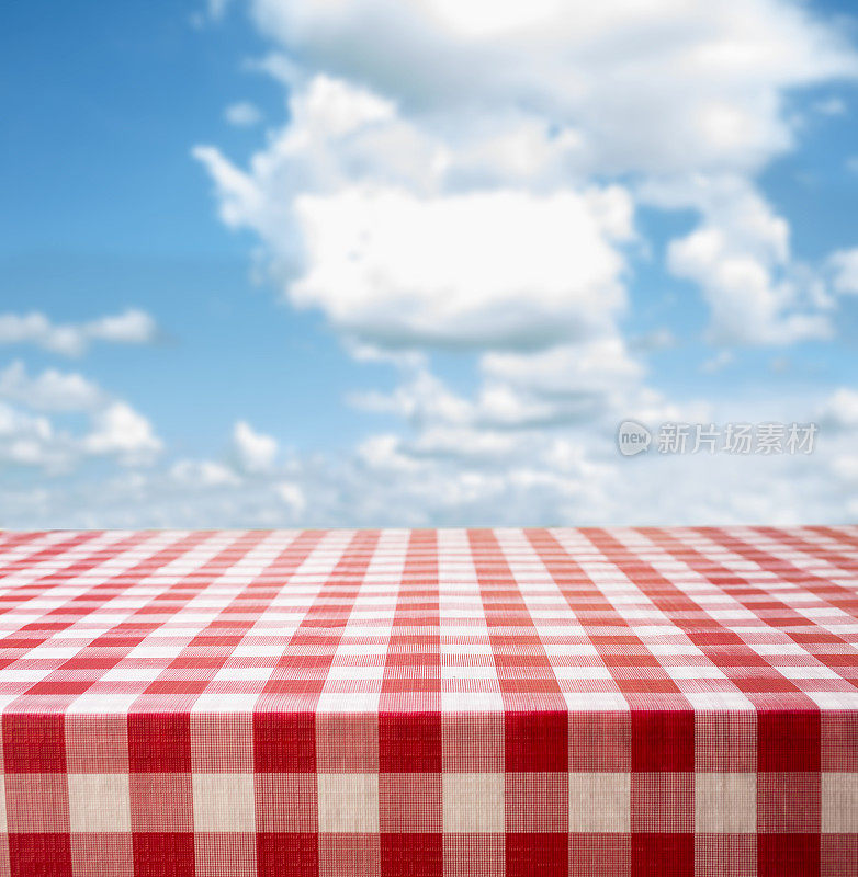野餐时间!红色格子桌布，夏日多云的蓝天。