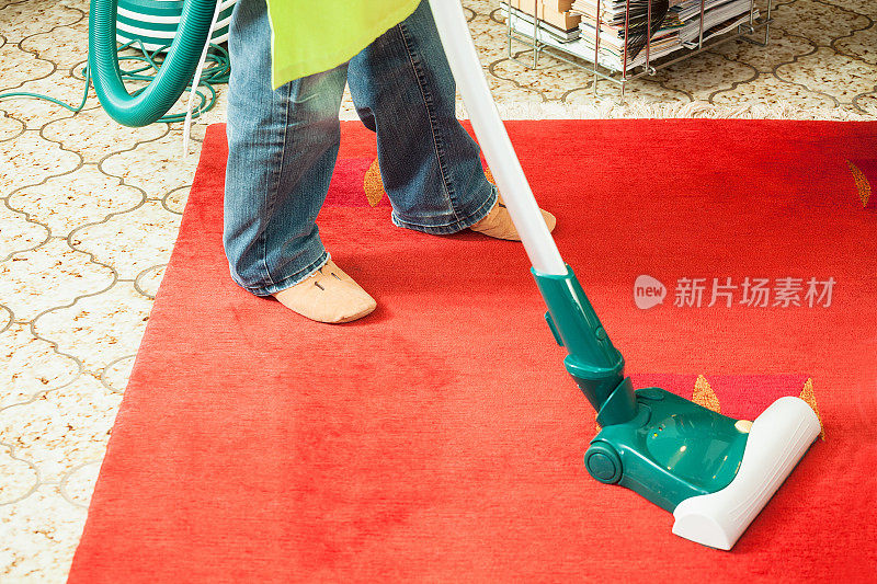 女人用吸尘器清扫红地毯
