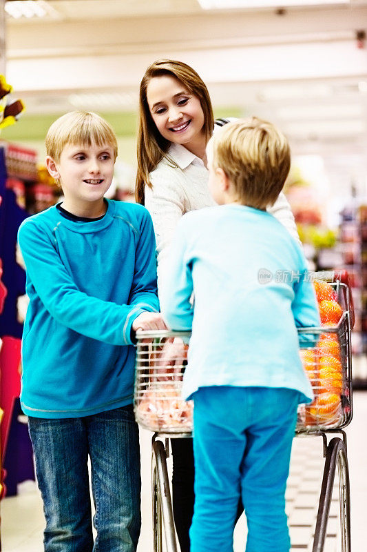 快乐的母亲，儿子，女儿在超市购物之旅。