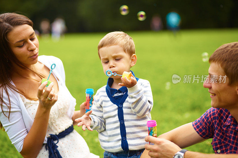 有吸引力的年轻父母吹泡泡与他们的乐趣