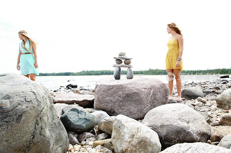 两个少女和Inukshuk站在海滩上