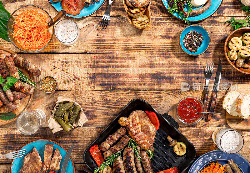开胃的烧烤牛排，香肠和烤蔬菜在一个木制的野餐桌上复印空间