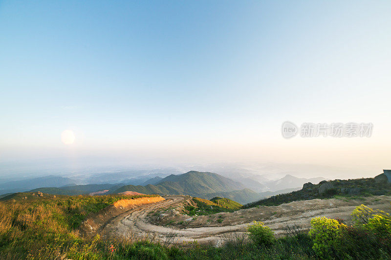 在夕阳下转弯泥泞的道路，轮胎印为汽车商业