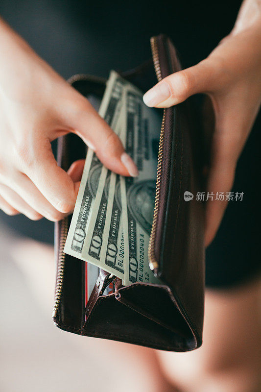 一个女人正在从钱包里取出钱