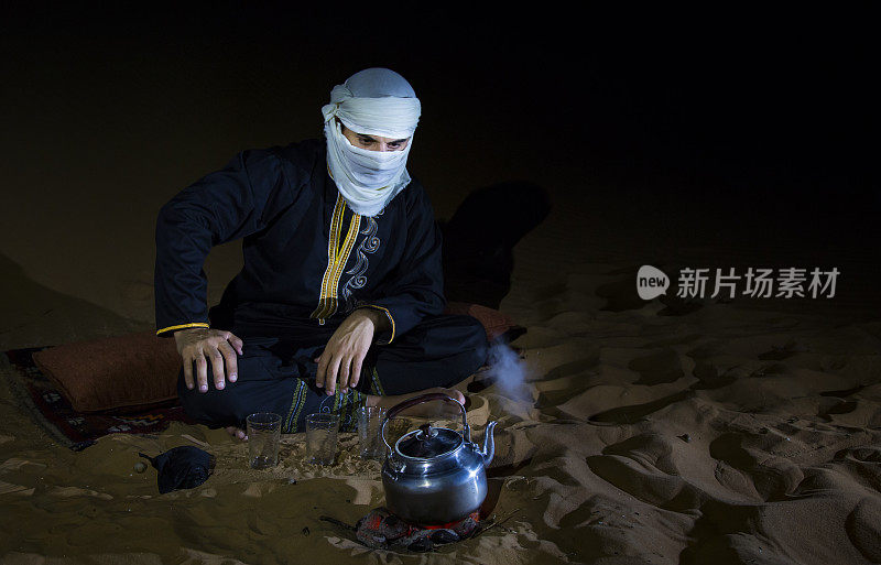 一个穿着传统图阿雷格服装的人在沙漠里泡茶