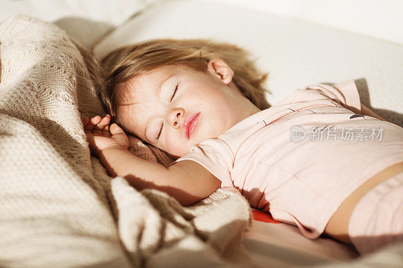 无忧无虑睡觉的小宝贝，床上有一个柔软的玩具。一个美丽的熟睡的孩子在针织毯子上的特写。甜美的梦