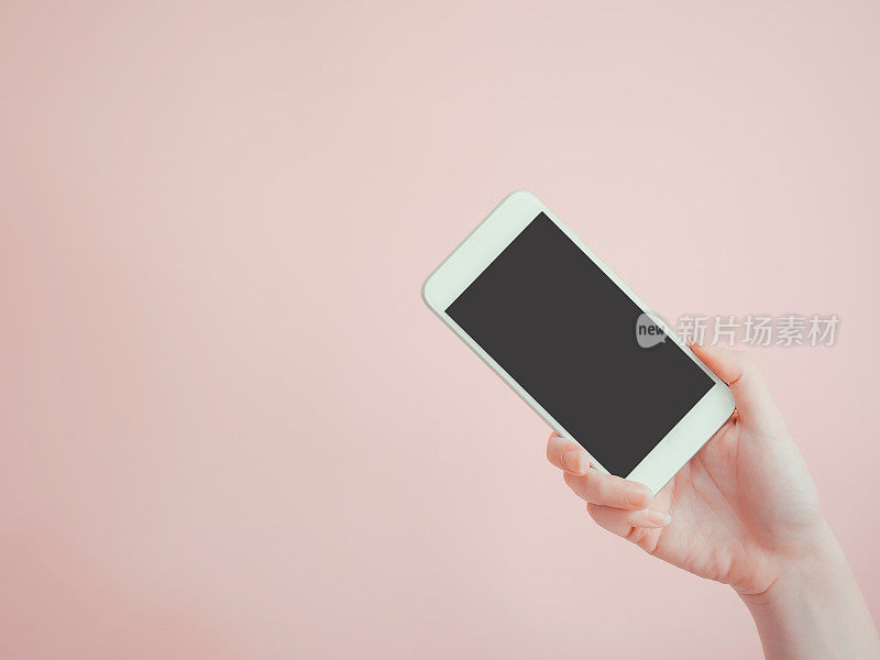 由亚洲女性美女右手手持并呈现在智能手机上的应用，以粉色粉彩为背景