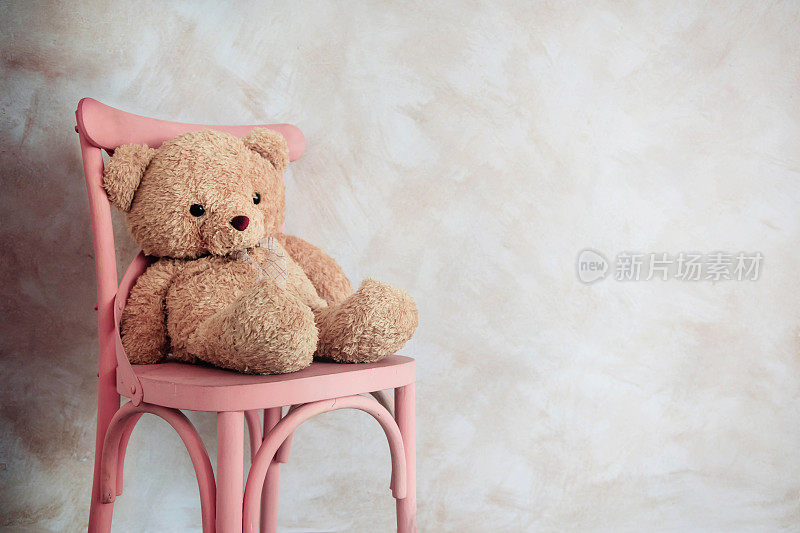 悲伤和孤独的概念。孤独的泰迪熊独自坐在屋里的椅子上