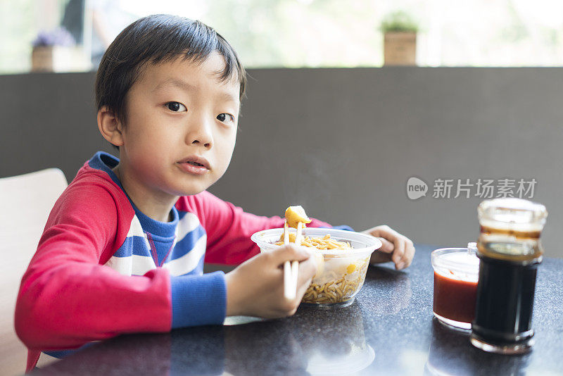 亚洲小孩用筷子吃美味的面条