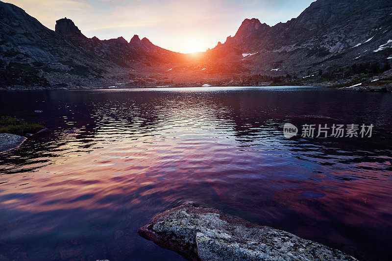 夕阳下美丽的山湖。夕阳西下，在奇迹般的山峦中，湖面由一石崩成。山泉