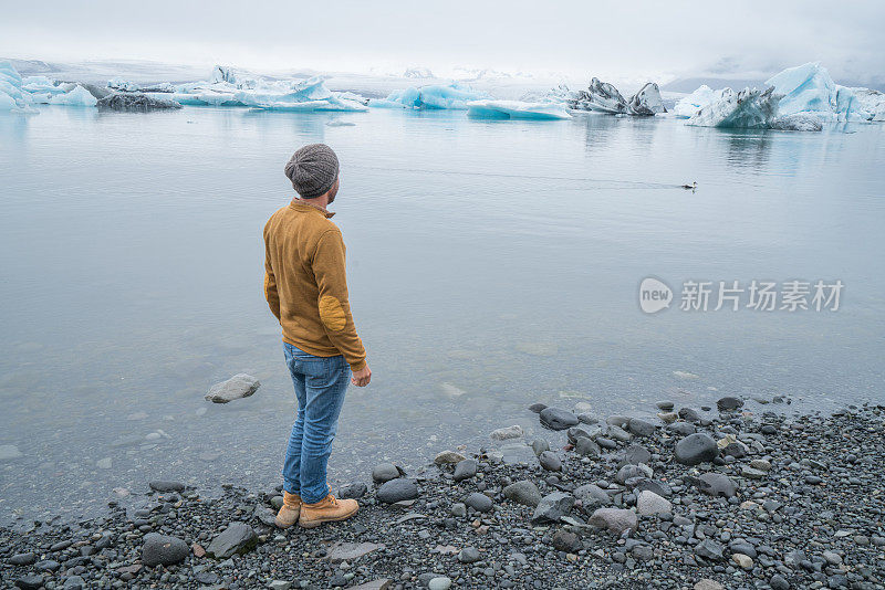 游客男性看冰川泻湖与冰山漂浮在湖上，冰岛旅游夏季概念