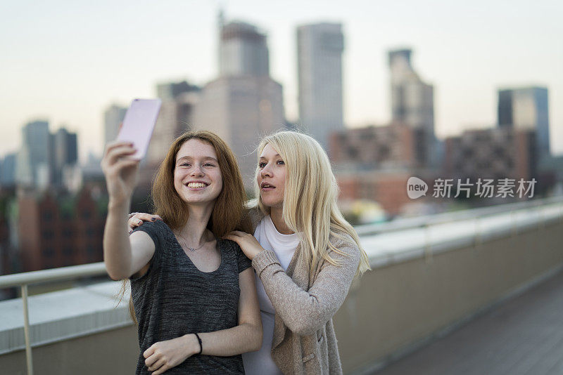 这位年轻漂亮的孕妇和她16岁的妹妹一起出去玩，用智能手机自拍，在屋顶上玩耍