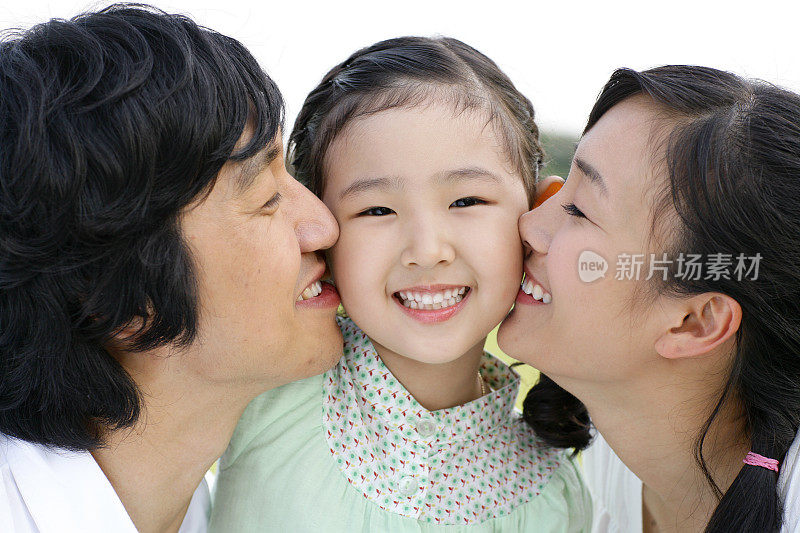 父母亲吻女儿(6-7岁)，特写镜头，微笑