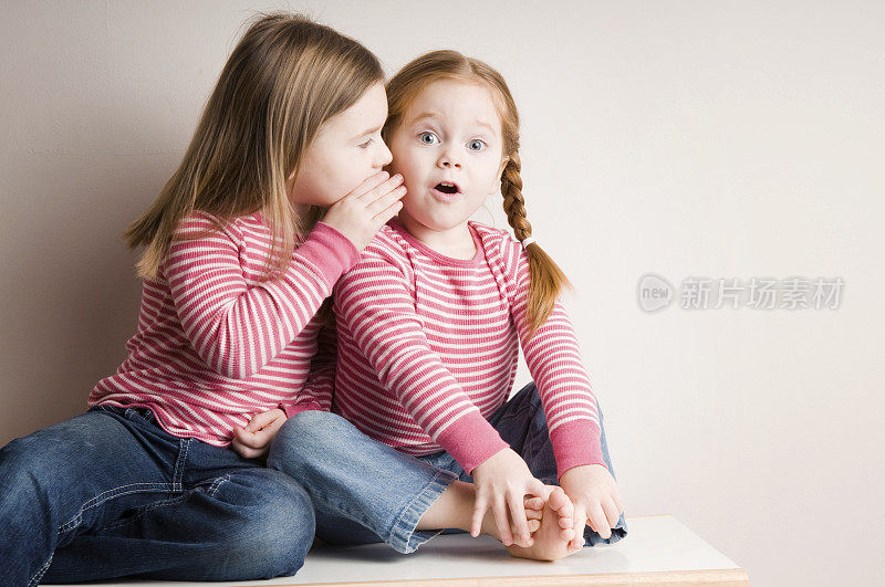 两个小女孩耳语着令人惊讶的秘密