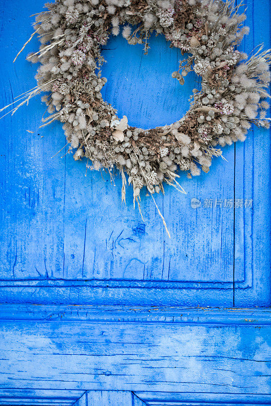 悬挂在蓝色木门上的干花花环