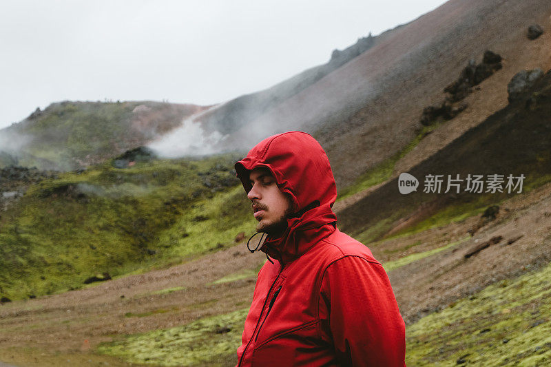 红色的男人在冰岛高地的地热地区徒步旅行