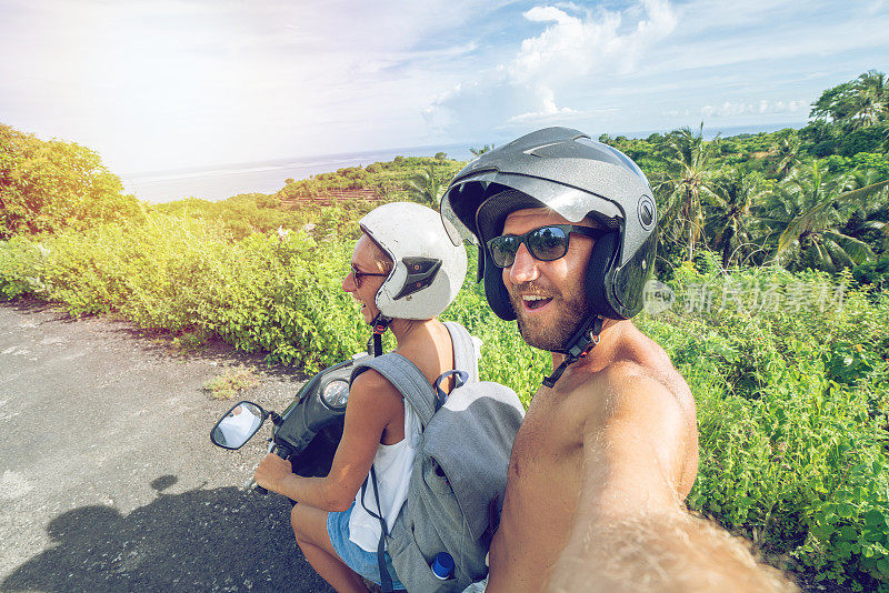 一对年轻夫妇在热带岛屿上骑摩托车自拍