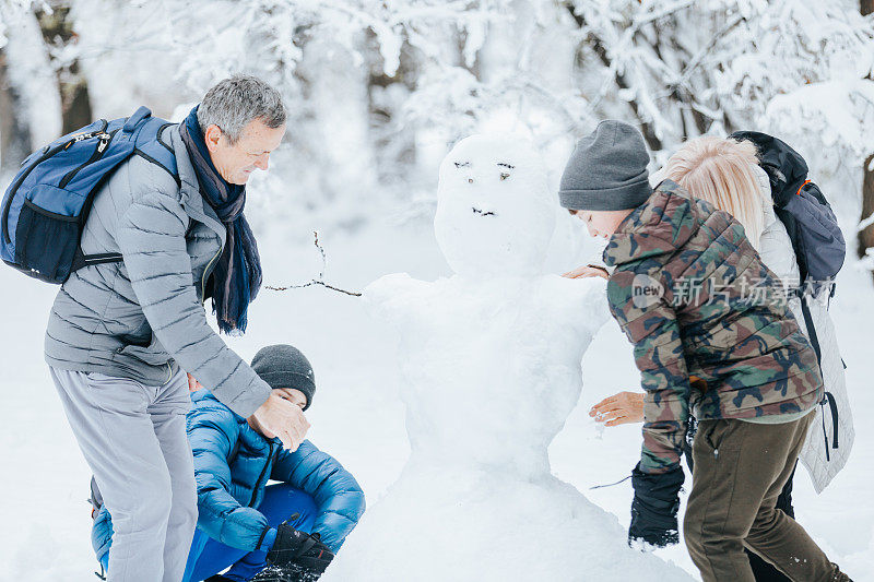 一家人在公园外面玩堆雪人