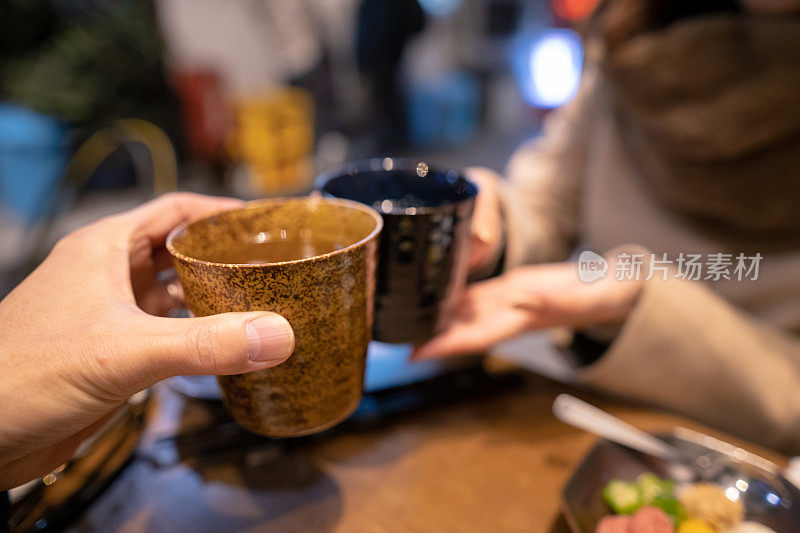 两个人在室外居酒屋用热酒精敬酒