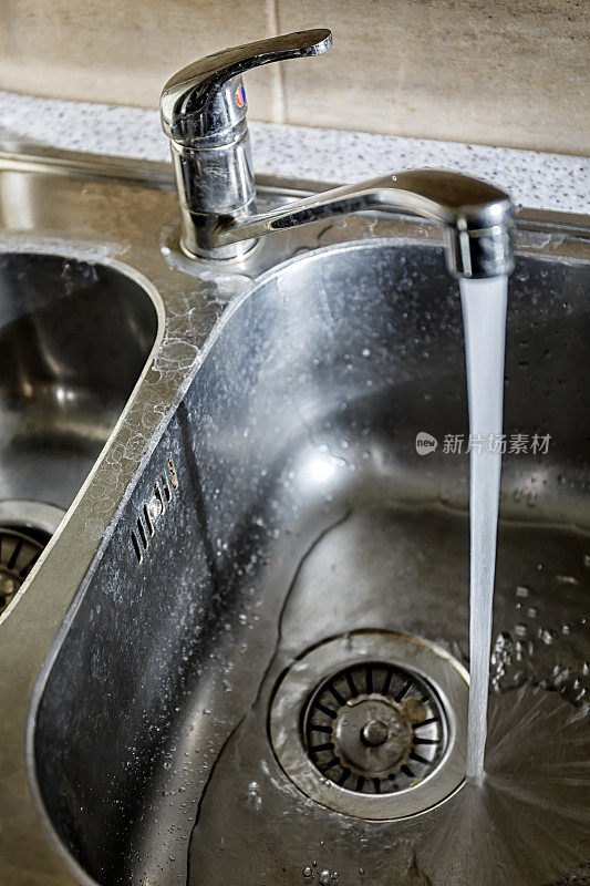 一个厨房水槽的特写与水垢和流动的水