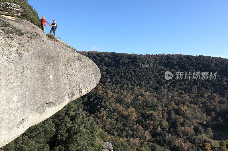 一对夫妇站在森林上方的悬崖峭壁上