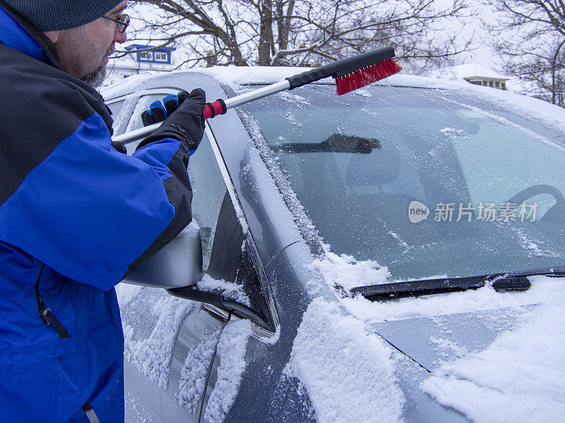 一名男子在刷车上的雪